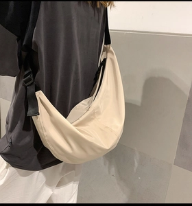 Detailed back view of a beige nylon crescent crossbody bag with adjustable black strap