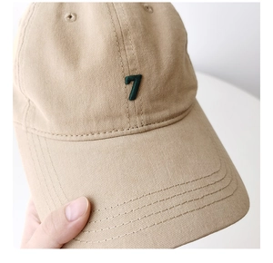 Close-up of khaki washed cotton baseball cap featuring green number 7 embroidery