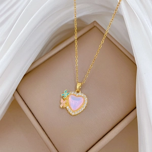 Detailed shot of gold heart necklace with pink stone and small butterflies in a box