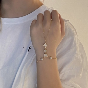 Macro view of gold slave bracelet featuring white butterfly and pearl details on hand