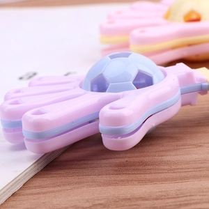 Close-up of macaron colored hand clapper toy with blue soccer ball center on desk