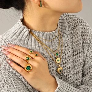 Detailed view of layered gold necklaces with green zircon pendants on a model