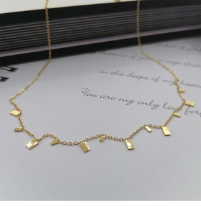 Close-up of gold titanium necklace featuring multiple rectangular pendants on a book