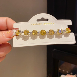 Detail shot of silver bracelet featuring seven large round yellow crystals on a display card