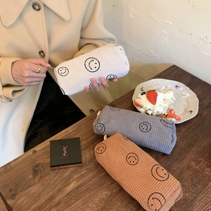 Detailed texture of corduroy cosmetic bags with embroidered smiley face in three colors