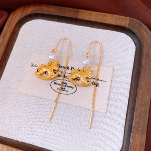 Detail of vintage gold rocking horse earrings with pearl accents on a rustic tray