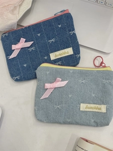 Portamonete in denim con fiocchi di raso rosa e ricami su una scrivania bianca
