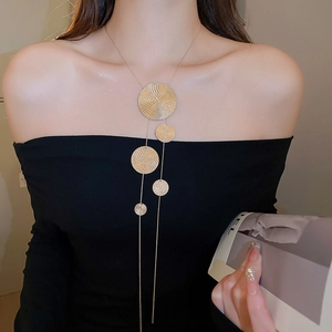 Détail d'un collier doré à plusieurs niveaux avec pendentifs circulaires texturés