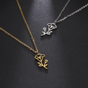 Detail of gold and silver stainless steel flower necklaces on a black background