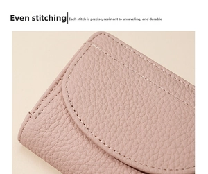 Détail du cuir rose grainé avec coutures blanches précises sur ce petit portefeuille