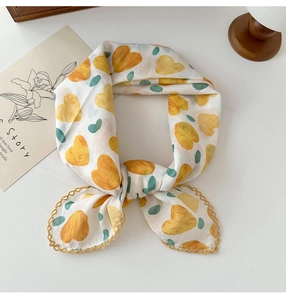 Detailed macro of white floral scarf with yellow heart patterns and gold lace trim