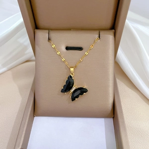 Macro detail of black butterfly pendant necklace with golden zircon trim in a jewelry box