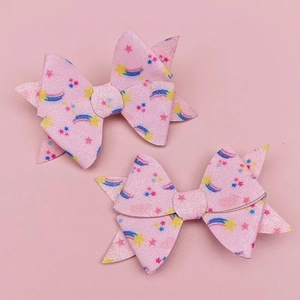 Close-up of pink glitter hair clips with rainbow and star patterns for children