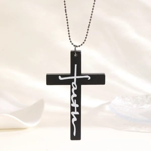 Macro view of a black wooden cross pendant with white faith text on a silver ball chain