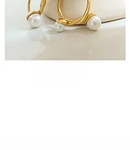 Close-up of twisted 18K gold plated C-shape earrings with elegant white pearls