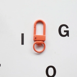Close-up of bright orange swivel clasp lobster hook with a rotating metal ring connector