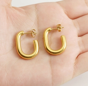 Close-up of elegant 18k gold-plated U-shaped earrings held in hand for detail