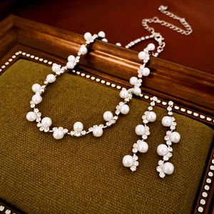 Detail of luxury pearl necklace and earrings set with rhinestones on green velvet