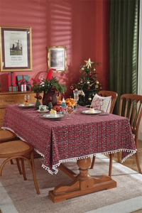 Close-up of Christmas plaid tablecloth featuring white pom-pom fringe and snowflake patterns