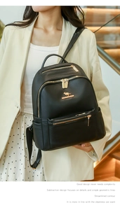 Detailed view of black leather backpack featuring gold kangaroo logo and zipper compartments