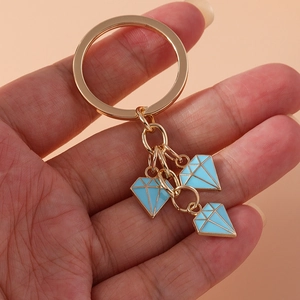 Golden metal keychain with three sky blue enamel diamond pendants held in hand