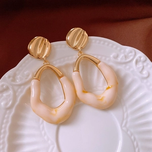 Detail of vintage oval resin earrings with marble pattern on a decorative relief tray