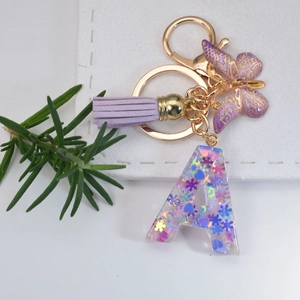 Detailed macro of crystal resin letter A keychain with purple sequins and butterfly charm