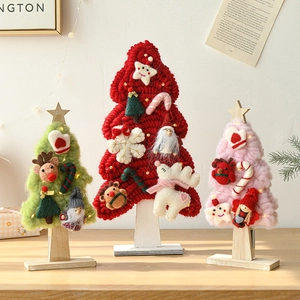 Handmade wool felt Christmas trees with deer and stars on a wooden stand