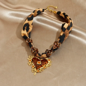 Collier ruban léopard avec pendentif cœur doré sur fond de soie couleur champagne
