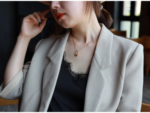 Detailed close-up of a minimalist gold teardrop pendant necklace worn by a female model