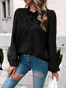 Detail of hollow embroidery on black blouse featuring ruffled collar and puff sleeves