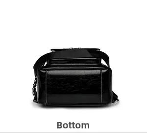 Flat bottom view of black glossy leather backpack with white stitching and metal chain