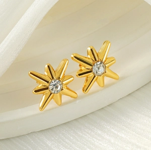 Detailed close-up of gold starburst stud earrings with sparkling central zircon stones