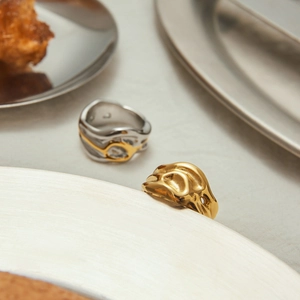 Detailed close-up of irregular molten gold and silver rings with organic lava texture