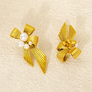 Detailed view of golden bow earrings featuring vertical rib texture and white pearls