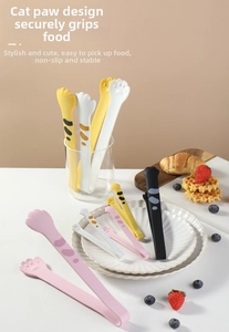 Detailed view of pink and yellow cat paw silicone food tongs on a white ripple plate