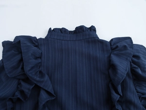 Detailed close-up of ruffle shoulders and stand collar on navy blue textured blouse