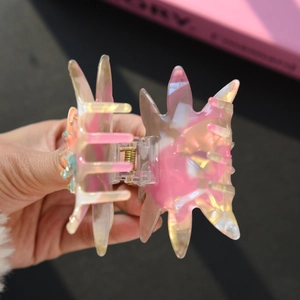 Détail d'une pince à cheveux florale translucide avec dégradé de rose et de jaune vif