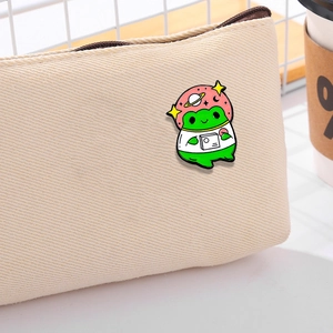 Cartoon frog astronaut enamel pin on beige canvas bag with starry helmet detail