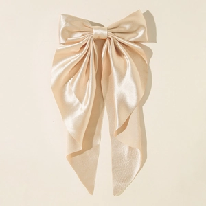 Detailed view of the champagne satin oversized bow hairclip with long hanging ribbons