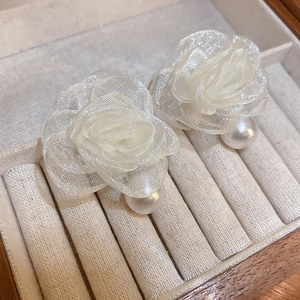 Detailed close-up of elegant white lace rose earrings with faux pearl drops in jewelry tray