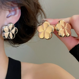Detailed view of 3D metallic flower earrings in polished gold and silver finishes