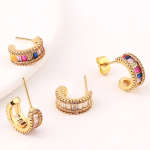 Golden C-shaped earrings with colorful and clear pavé crystals on white background