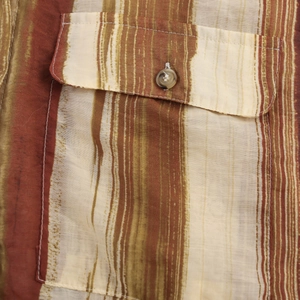 Détail d'une poche de chemise à rayures marron et beige avec un bouton beige brillant et couture