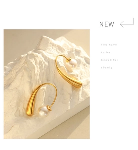 Detail of elegant gold drop earrings with pearls on white stone aesthetic background
