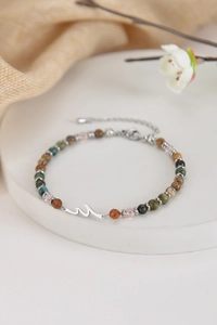 Detail of natural stone wave bracelet with silver charm and adjustable metal clasp