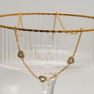 Elegant gold heart pendant necklace with three crystal-encrusted charms on a fine chain
