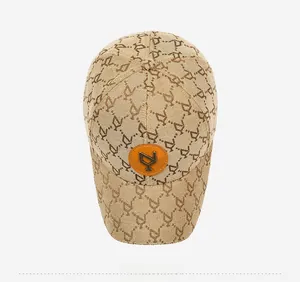 Top view of beige baseball cap with brown geometric logo jacquard and orange leather patch