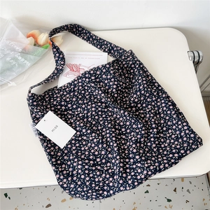 Close-up of floral canvas tote bag with small pink flowers and MISS tag on white table