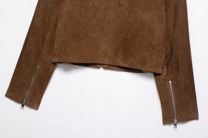 Détail de l'ourlet et des manches d'une veste en daim marron avec fermetures éclair